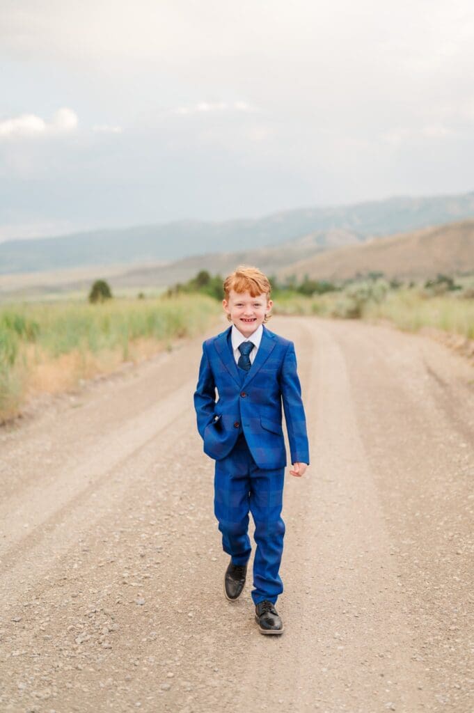 Child in navy blue suit grinning during LDS baptism session in southeast Idaho