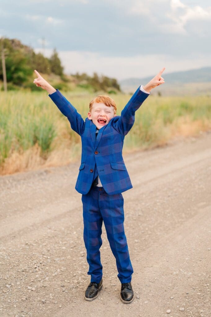 Child in navy blue suit grinning during LDS baptism session in southeast Idaho